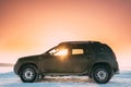 Sunrays Through Window Of Car Renault Duster Or Dacia Duster Suv Parked On Winter Snowy Field At Sunset Dawn Sunrise