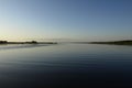 Sunrise above a river on foggy summer morning, the sky reflections in the water, misty reflection in steaming water,