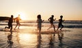 Sunrise, beach and friends with freedom, running and having fun in water together on summer vacation. Ocean, silhouette Royalty Free Stock Photo