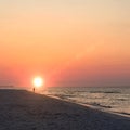 Sunrise at the Beach with One Person Walking Along the Shoreline. Royalty Free Stock Photo