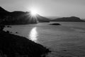 Sunrise from behind the mountains against the backdrop of the sea and the Istavers. Black and white image.