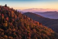 Sunrise on the Blue Ridge Parkway in Autumn illuminating colorful trees on the hillside.