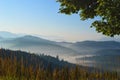 Sunrise in Carpathian mountains. Silhouettes of mountain peaks and morning fog in the background. Grass in the foreground