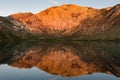 Sunrise casts golden light on mountain peaks reflected in the calm waters of alpine lake Royalty Free Stock Photo