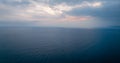 Sunrise color peaks through clouds over calm ocean landscape