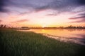 Sunrise or dawn above the pond or lake at spring or early summer morning with cloudy sky, fog over water and reed grass Royalty Free Stock Photo