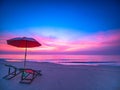 Sunrise with dramatic morning sky over sea with chair and umbrella on beach Royalty Free Stock Photo