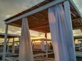 Sunrise in the early morning on the beach with closeup of white curtains on romantic wooden sunshades house parasol beach Royalty Free Stock Photo