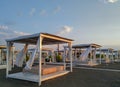 Sunrise in the early morning on the beach with closeup of white curtains on romantic wooden sunshades house parasol sandy beach Royalty Free Stock Photo