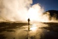 Sunrise at El Tatio Geysers with a tourist walking between the fumaroles in the Atacama desert, Chile