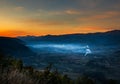 Sunrise with fog, mountains and town in the background Royalty Free Stock Photo