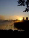 Sunrise on a foggy lake. The morning city in a haze in the background. Mirror surface of water Royalty Free Stock Photo