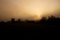 Sunrise with freezing fog on a cold winter morning. Farm and houses silhouetted