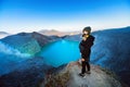 Girl stand on rock above volcano Kawah Ijen acid lake