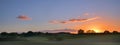 sunrise with glowing clouds over a wide rural landscape with meadows and trees in the morning mist, panorama format with copy spa Royalty Free Stock Photo