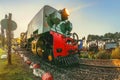 At sunrise a green narrow gauge steam locomotive`s boilers is been stocked for the days transportation on a farm in South Africa