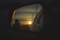 Sunrise on highway road in left side view mirror driver. Focus on reflection in smaller mirror. Royalty Free Stock Photo