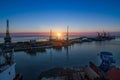 Sunrise illuminates sea port, cargo ships docked at berth. Industrial cranes against dawn sky. Freight containers ready Royalty Free Stock Photo