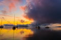 Sunrise on the lake with boats, reflection of sun in water, with fog and clouds on summer morning Royalty Free Stock Photo