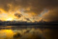 Sunrise on the lake, reflection of sun in water, with fog and clouds on summer morning Royalty Free Stock Photo