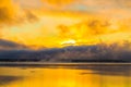 Sunrise on the lake, reflection of sun in water, with fog and clouds on summer morning Royalty Free Stock Photo