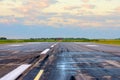 Sunrise with landscape airport of wet runway with traces of rubber tires on asphalt.