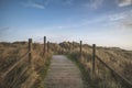 Beautiful sunrise landscape image of sand dunes system over beach with wooden boardwalk Royalty Free Stock Photo