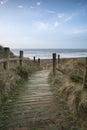 Beautiful sunrise landscape image of sand dunes system over beach with wooden boardwalk