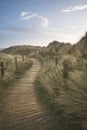 Beautiful sunrise landscape image of sand dunes system over beach with wooden boardwalk