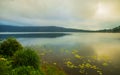 Sunrise landscape. Lake surrounded by mountains and hills. Rainy cloudy weather. Water reflection. Bratan lake, Bedugul, Bali, Royalty Free Stock Photo