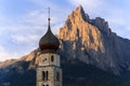 Sunrise landscapes of Church St. Valentin on grassy hilltop with view of rugged peaks of Mountain Schlern with alpenglow in backgr