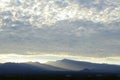 Sunrise light rims edge of massive cloud bank over Spring Mountains and the Mount Charleston peak with misty valleys Royalty Free Stock Photo