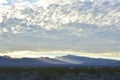 Sunrise light rims edge of massive cloud bank over Spring Mountains and the Mount Charleston peak with misty valleys Royalty Free Stock Photo