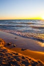 Sunrise lighting of a lake or ocean lapping against a sandy beach shore