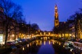 Morning blue sunrise on Amsterdam canal with Church bell tower on the background horizon