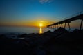 Sunrise over the beach with the pont del petroli and the rocks as a company