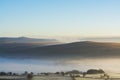 sunrise over Dartmoor with Tors in view and mist rolling over hills Royalty Free Stock Photo