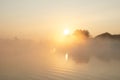 Sunrise over the foggy lake with the reflection of sun and trees in the water. Early fresh morning landscape. Mist on the water, Royalty Free Stock Photo