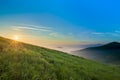 Sunrise Over Hills In Mountains With Green Grass And Blue Sky Wi
