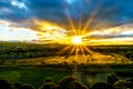 Sunrise over the horizon with sun peeking under dark morning clouds Royalty Free Stock Photo