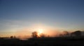 Sunrise over mist covered farmland stream