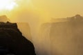 Sunrise over the mist and water dust of Victoria Falls in shades of red, orange and yellow Royalty Free Stock Photo
