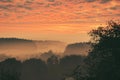 Sunrise over a misty forest. Dawn in fairy forest with dramatic glowing sky