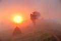 Sunrise over mountain field. Haystacks in misty autumn morning h Royalty Free Stock Photo