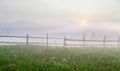 Sunrise over the mountains in fog, view from a meadow. Royalty Free Stock Photo