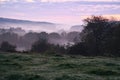 Sunrise over a neighboring forest with meadow in the foreground. Pasture landscape Royalty Free Stock Photo