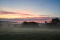 Sunrise over a neighboring forest with meadow in the foreground. Pasture landscape Royalty Free Stock Photo