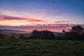 Sunrise over a neighboring forest with meadow in the foreground. Pasture landscape Royalty Free Stock Photo