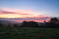 Sunrise over a neighboring forest with meadow in the foreground. Pasture landscape Royalty Free Stock Photo