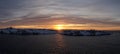 Sunrise over the ocean at Henningsvaer Stadium with snow capped mountains and a lighthouse during winter on the Lofoten Islands of Royalty Free Stock Photo